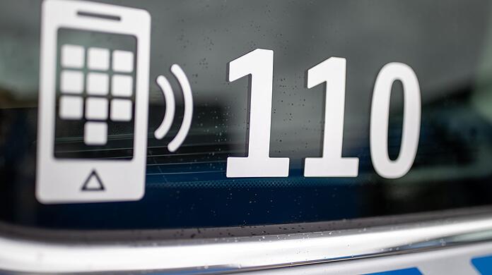 Der Nummer des Polizeinotrufs 110 steht auf der Scheibe eines Polizeifahrzeugs.