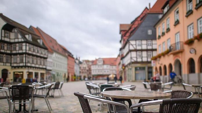 Unbesetzte Tische und Stühle eines geschlossenen Kaffees auf einem Marktplatz.