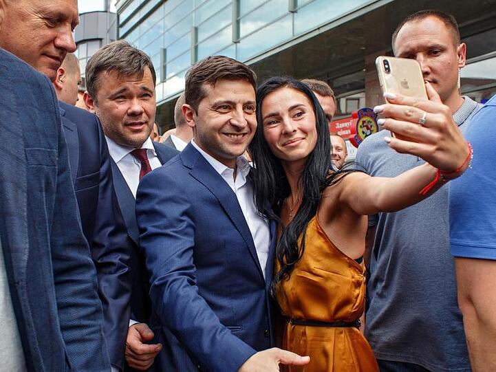 Wolodymyr Selenskyj (3.v.l), Präsident der Ukraine, lässt sich mit einer Frau für ein Selfie fotografieren.