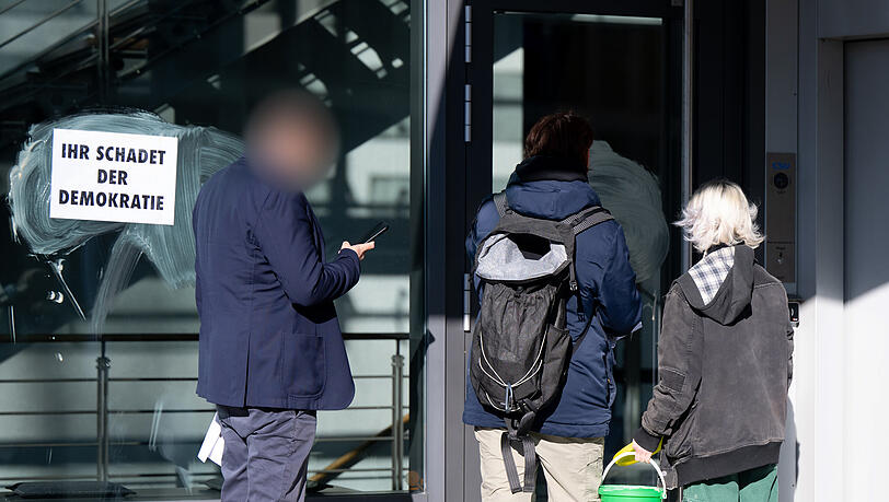 Zwei Aktivisten (M. und r.) kleben an der CSU-Zentrale Plakate mit der Aufschrift "Ihr schadet der Demokratie" an die Fensterscheiben. Die Protestaktion richtet sich gegen die Abstimmung der Union mit der AfD im Bundestag.