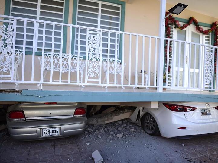 Zerstörte Autos stehen unter einem Haus, das nach einem Erdbeben teilweise eingestürzt ist.