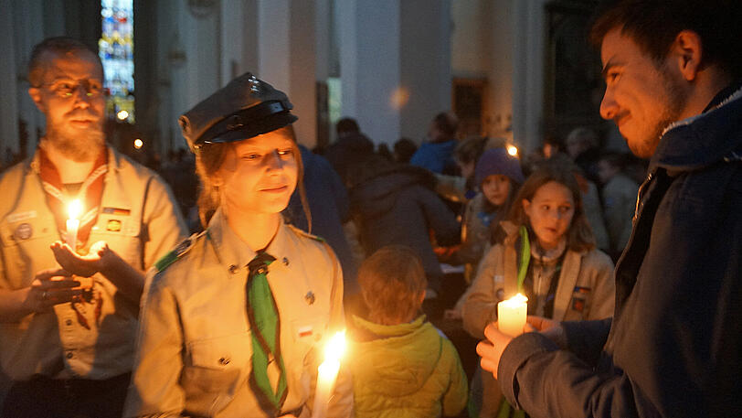 Pfadfinder in der Frauenkirche mit dem Friedenslicht von Bethlehem, das an Gläubige weitergegeben wird.