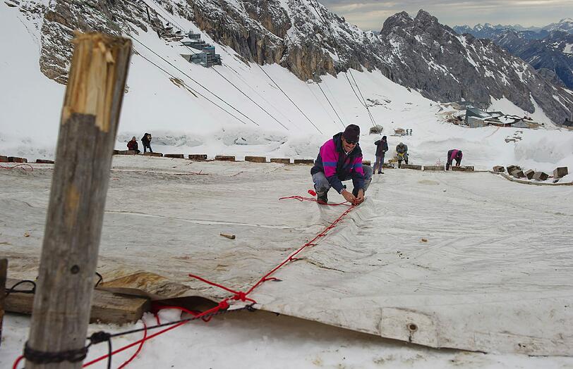 Arbeiter decken auf dem Zugspitzplatt bei Grainau den Gletscher mit einer Plane ab, um ein Abschmelzen zu verhindern. Deutschlands einziger Gletscher soll waehrend der warmen Sommermonate mit der 500 bis 600 Quadratmeter grossen Plane vor Sonne und Regen geschuetzt werden.