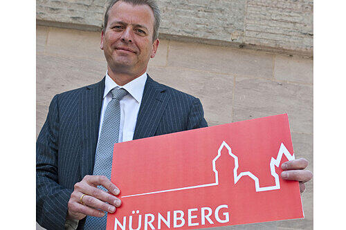 OB Ulrich Maly posiert mit dem neuen Logo der Stadt.