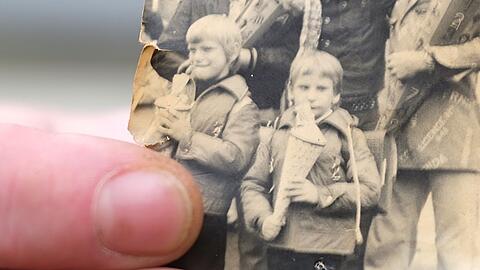 Kai Oppermann, in DDR-Kinderheimen groß geworden, zeigt ein Foto von seiner Einschulung. In der Bildmitte ist er in der vorderen Reihe mit Zuckertüte zu sehen. Links daneben steht sein Bruder Patrick.