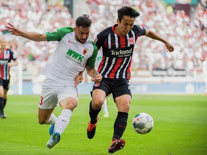 Marco Richter von Augsburg und Makoto Hasebe von Frankfurt (l-r.) im Zweikampf um den Ball. Foto: Matthias Balk