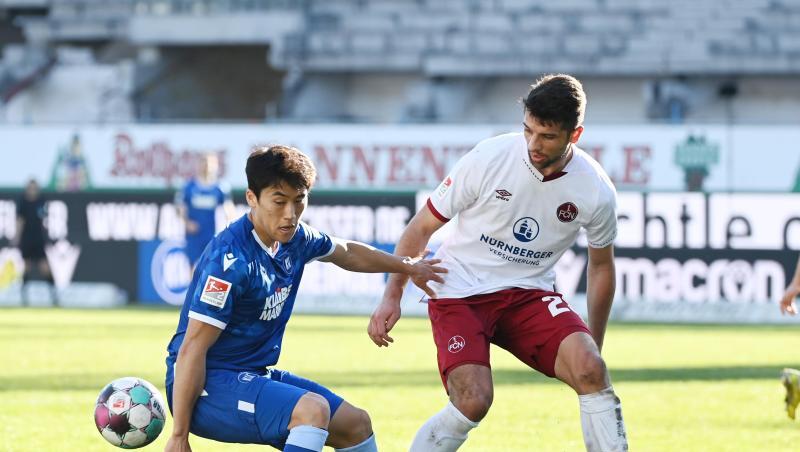Der Karlsruher Kyoung-rok Choi (l) und der Nürnberger Lukas Mühl kämpfen um den Ball.