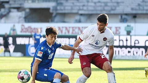 Der Karlsruher Kyoung-rok Choi (l) und der Nürnberger Lukas Mühl kämpfen um den Ball.