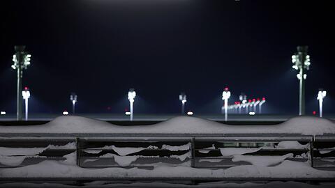 Flutlichter stehen hinter einem schneebedeckten Parkhaus am Münchener Flughafen.