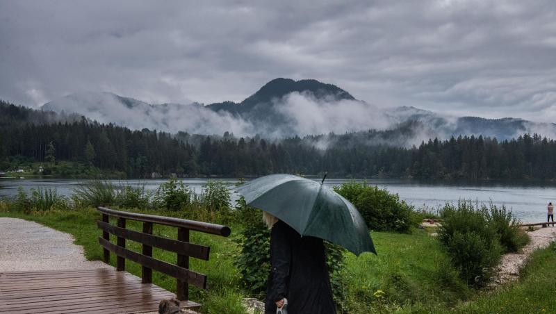 Eine Frau geht bei Regen mit ihrem Hund am Hintersee in Ramsau Bei Berchtesgaden spazieren. Eine Frau geht bei Regen mit ihrem Hund am Hintersee in Ramsau Bei Berchtesgaden spazieren.