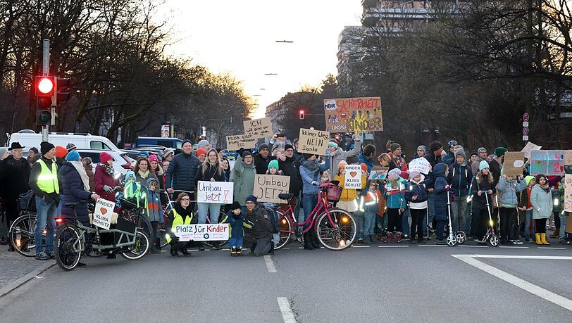 Rund 200 Eltern und Kinder demonstrieren Donnerstag früh vor Schulbeginn für einen Umbau der Karl-Theodor-Straße. Die Pläne dafür liegen schon seit Jahren vor, im Februar diskutiert der Stadtrat erneut darüber.