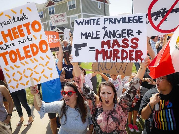Demonstranten protestieren außerhalb des Miami Valley Hospital in Dayton singend gegen die Ankunft von Präsident Trump.