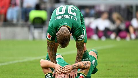 Niklas Dorsch vom FC Augsburg steht über seinem Teamkollegen Mads Pedersen.