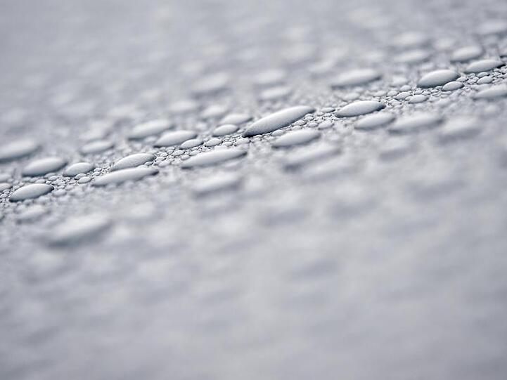 Nach einem Regenschauer perlen Wassertropfen auf einer Motorhaube. Foto: Patrick Pleul/dpa-Zentralbild/dpa/Symbolbild
