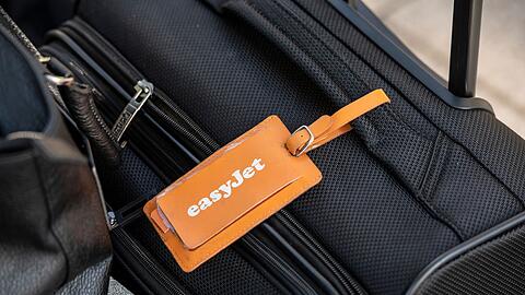 Ein Adressanhänger mit dem Logo von Easyjet ist an einem Koffer befestigt.