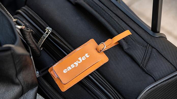 Ein Adressanhänger mit dem Logo von Easyjet ist an einem Koffer befestigt.