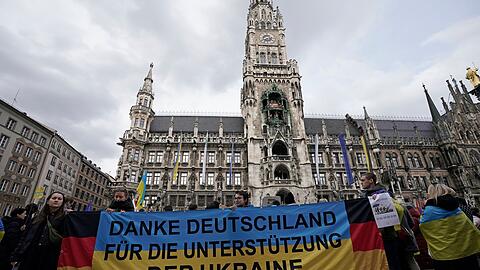Teilnehmer einer Kundgebung anlässlich des zweiten Jahrestags des russischen Angriffskriegs auf die Ukraine stehen mit einem Banner "Danke Deutschland für die Unterstützung der Ukraine" auf dem Marienplatz.
