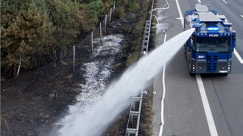 27.07.2018: : Ein Wasserwerfer der Polizei löscht am Rande eines Waldgebietes auf der Autobahn. Der Waldbrand bei Potsdam ist zwar erstmal unter Kontrolle, der Kampf gegen die Flammen geht aber unvermindert weiter.