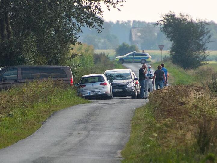 Mitarbeiter der Spurensicherung stehen auf einem Weg in der Nähe des Resthofs des Tatverdächtigen in Nordfriesland.