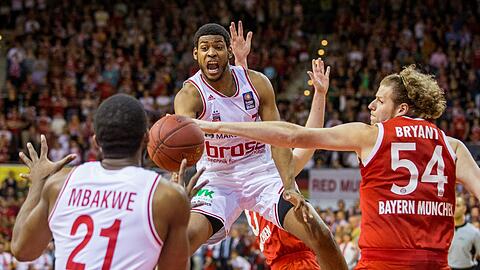 John Bryant (r) von München im Kampf um den Ball mit Trevor Mbakwe (l) und Ryan Thompson von Bamberg.