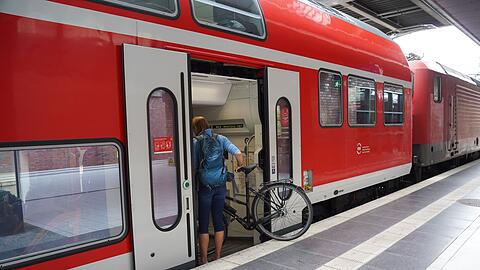 Eine Reisende steigt mit ihrem Fahrrad in eine Regionalbahn Richtung Rostock.