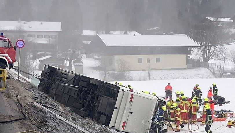 Einsatzkräfte der Feuerwehr stehen auf der Bundesstraße B306 neben einem umgekippten Reisebus.