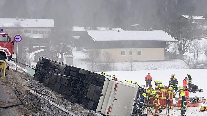 Einsatzkräfte der Feuerwehr stehen auf der Bundesstraße B306 neben einem umgekippten Reisebus.
