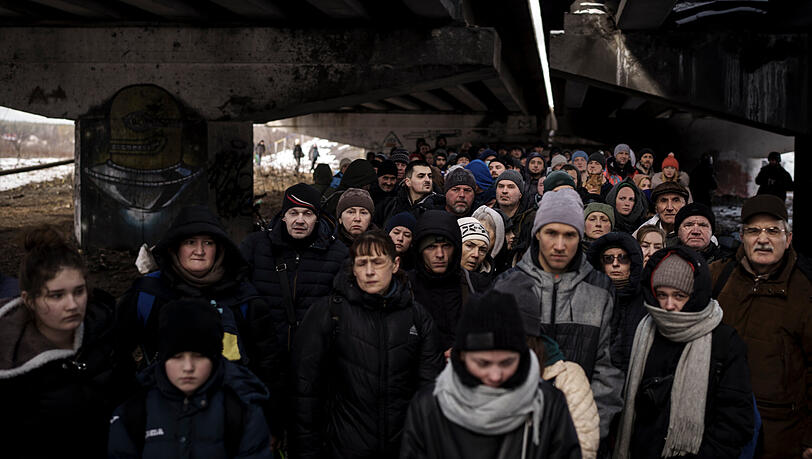 Ukrainer drängen sich unter einer zerstörten Brücke, als sie versuchen, in den Außenbezirken von Kiew über den Fluss Irpin zu fliehen.