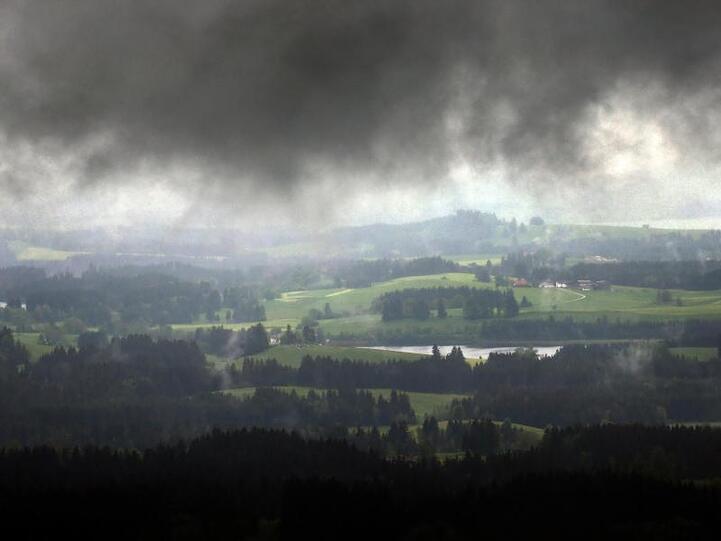 Durch eine Wolkenlücke wird das Alpenvorland von der Sonne beschienen. Foto: Karl-Josef Hildenbrand/Archiv