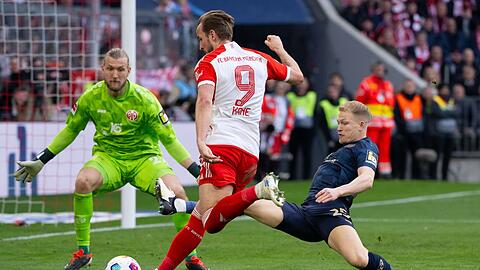 Harry Kane (M) von München und Andreas Hanche Olsen (r) und Robin Zentner von Mainz kämpfen um den Ball.