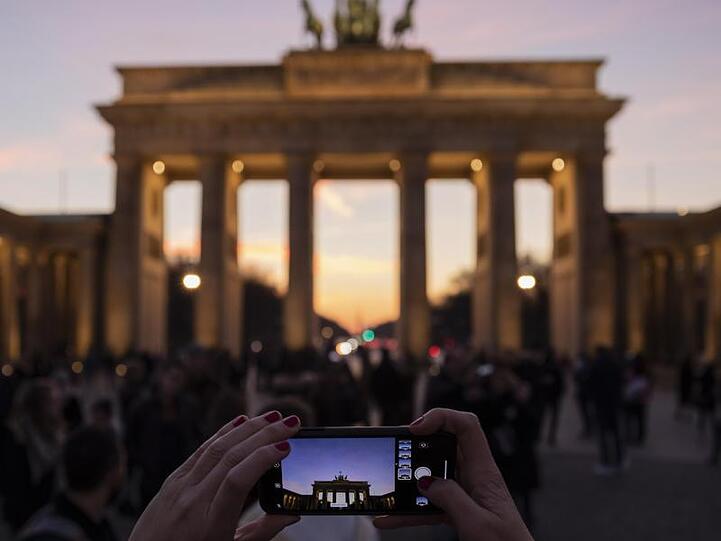 Eine Frau fotografiert das Brandenburger Tor in der Abenddämmerung.