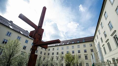 Ein Kreuz steht auf dem Rasen im Innenhof des Erzbistums München.