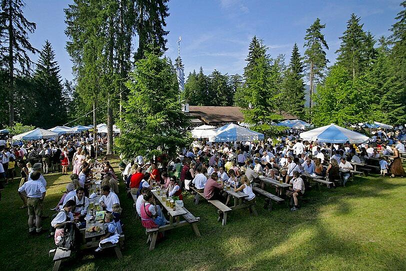 Die Hirschbergler aus Kreuth feiern vor der Trachtenhütte. Wenn&rsquo;s dunkel wird, rollen die Party-Busse aus München bei den Waldfesten an &ndash; dann geht es rund.