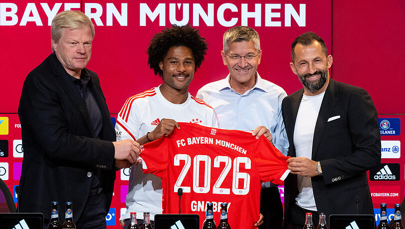 Fröhliche Gesichter bei der PK in der Allianz Arena: Oliver Kahn (l-r), Serge Gnabry, Herbert Hainer und Hasan Salihamidzic zeigen Gnabrys Trikot mit der 2026 – der Offensiv-Star hat für weitere vier Jahre in München unterschrieben.