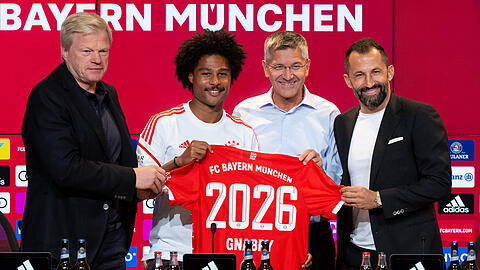 Fröhliche Gesichter bei der PK in der Allianz Arena: Oliver Kahn (l-r), Serge Gnabry, Herbert Hainer und Hasan Salihamidzic zeigen Gnabrys Trikot mit der 2026 – der Offensiv-Star hat für weitere vier Jahre in München unterschrieben.