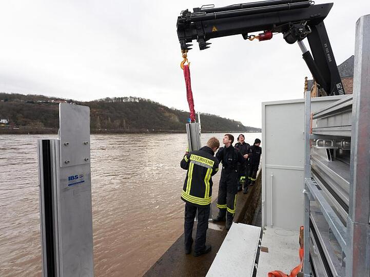 Im Koblenzer Stadtteil Neuendorf wird der Scheitelpunkt noch erwartet. Feuerwehrleute stellen eine mobile Hochwasserschutzmauer auf.