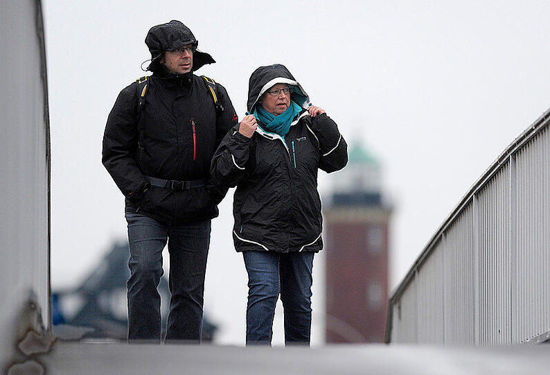 Ein Paar in Regenkleidung überquert am 08.01.2015 eine Fußgängerbrücke im Hafenbereich von Cuxhaven (Niedersachsen).