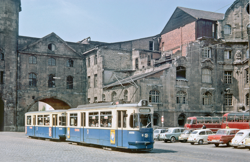 1964 stehen immer noch große Teile des riesigen Verkehrsministeriums, inklusive Torbau über der Arnulfstraße, durch den hier gerade eine 3er-Tram Richtung Schwabing fährt.