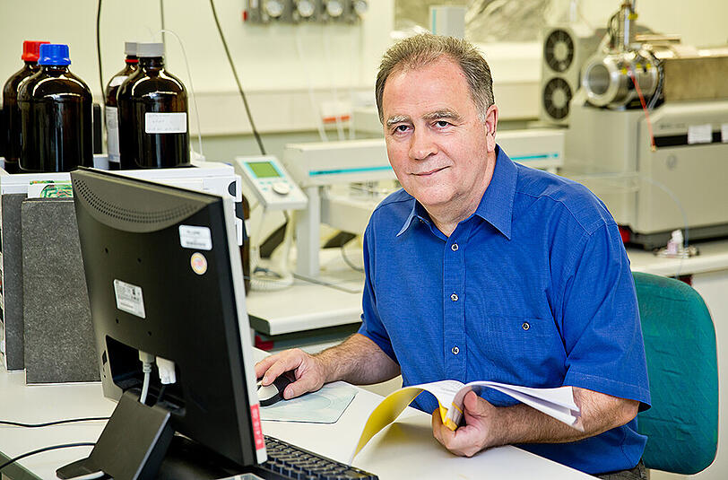 Ein Pharmakologe wertet im Labor Probenmaterial am Computer aus. Im Hintergrund ist ein Massenspektrometer zu erkennen, mit dem man Dopingstoffe in geringsten Konzentrationen messen kann.