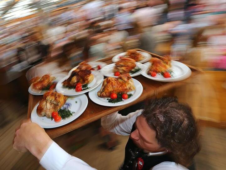 Diät geht anders: Kellner auf dem Oktoberfest mit einem Tablett Hendl (Hähnchen).