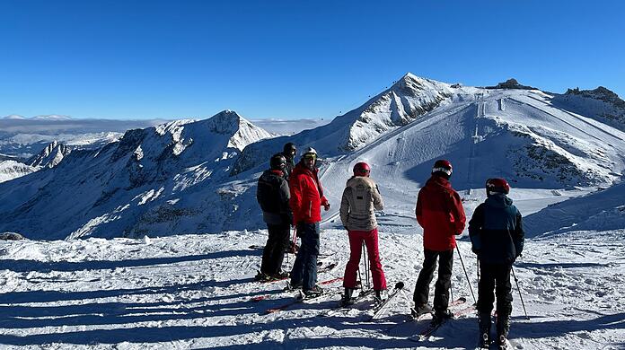Wintersportler schauen auf ein Skigebiet.