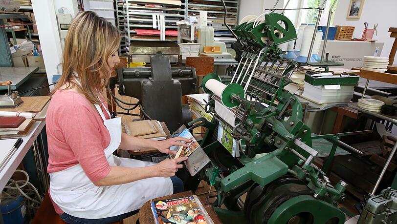 Andrea Fellinger sitzt an einer über hundert Jahre alten Maschine aus Leipzig. Hier bindet sie Comics aus der ehemaligen DDR. Andrea Fellinger sitzt an einer über hundert Jahre alten Maschine aus Leipzig. Hier bindet sie Comics aus der ehemaligen DDR.