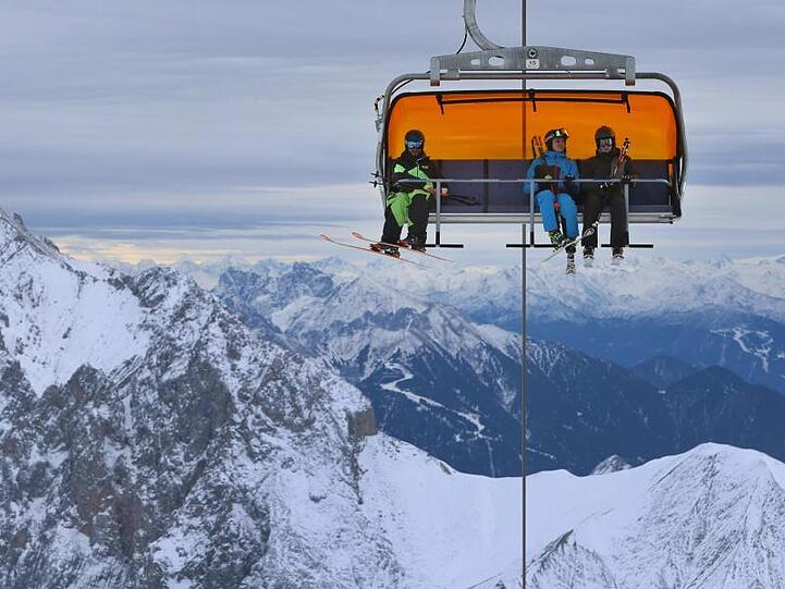 Wintersportler sitzen auf der Zugspitze in einem Sessellift. Foto: Karl-Josef Hildenbrand/Archiv
