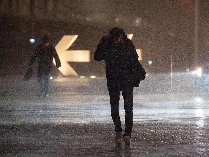 Passanten kämpfen sich durch strömenden Regen.