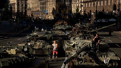 Menschen inspizieren zerst&ouml;rte russische Milit&auml;rfahrzeuge, die in der Innenstadt von Kiew aufgestellt sind.