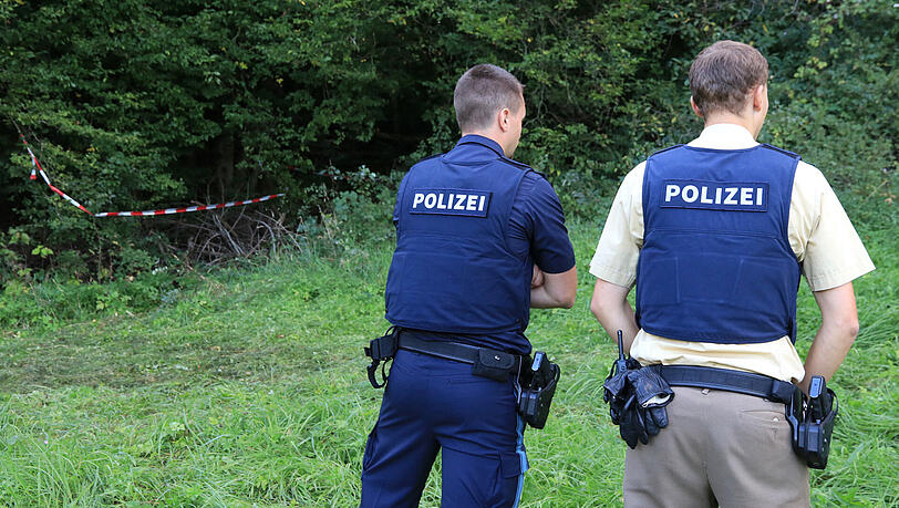 Zwei Polizisten bewachen den Fundort der Leiche in einem Wald. Zwei Polizisten bewachen den Fundort der Leiche in einem Wald.