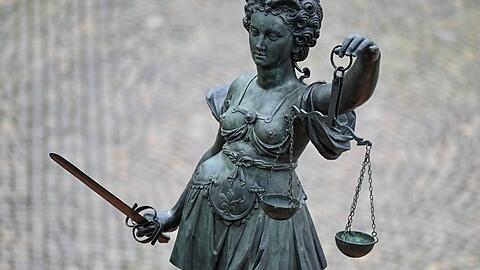 Eine Statue der Justitia hält eine Waage und ein Schwert in der Hand.