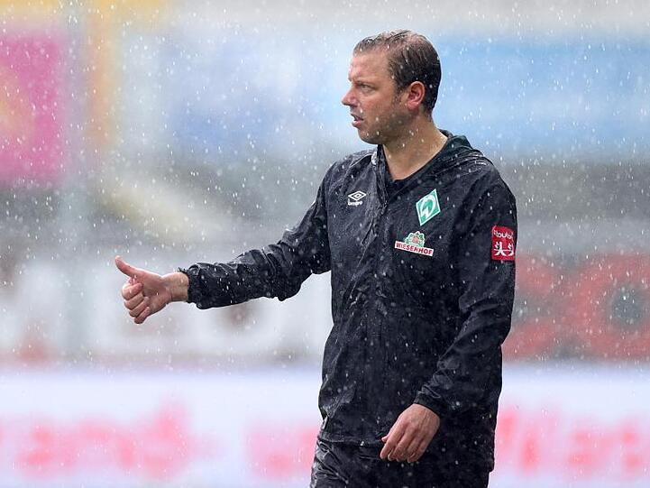 Florian Kohfeldt von Werder Bremen steht im strömenden Regen. Foto: Friedemann Vogel/EPA/Pool/dpa/Archivbild