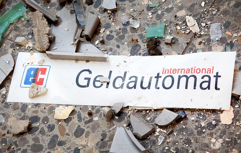 Splitter und ein Schild mit der Aufschrift "Geldautomat" liegen vor einem gesprengten Geldautomat. (Symbolbild)