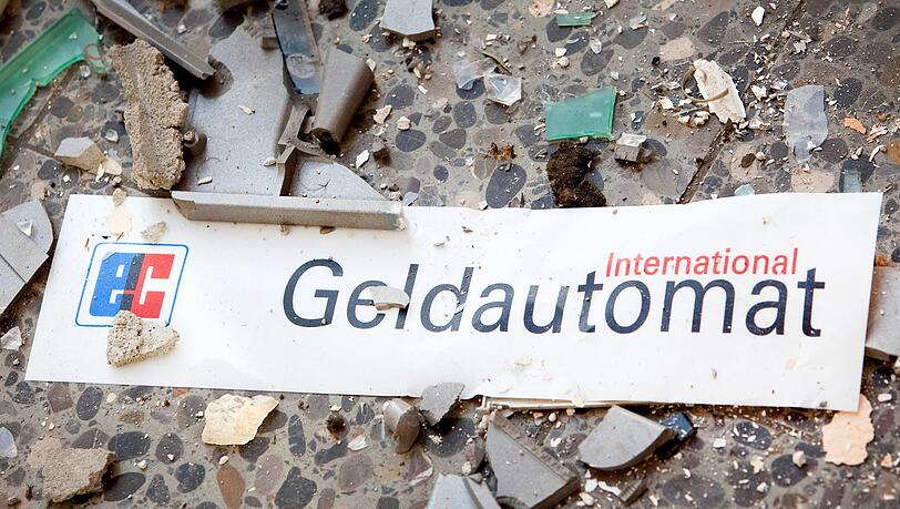 Splitter und ein Schild mit der Aufschrift "Geldautomat" liegen vor einem gesprengten Geldautomat. (Symbolbild) Splitter und ein Schild mit der Aufschrift "Geldautomat" liegen vor einem gesprengten Geldautomat. (Symbolbild)